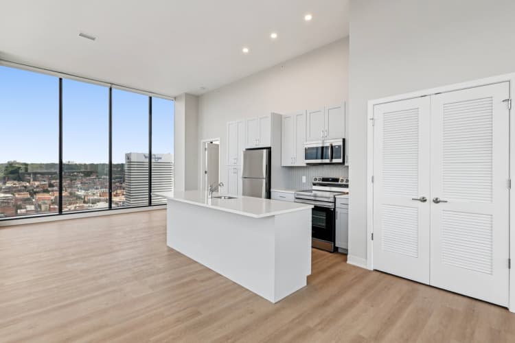 Cincinnati apartments for rent - image - A kitchen with white cabinets and a large window overlooking a cityscape.