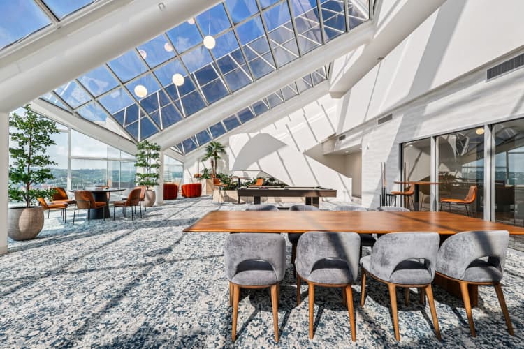 Cincinnati apartments for rent - image - A modern dining room with a glass ceiling and a long wooden table.