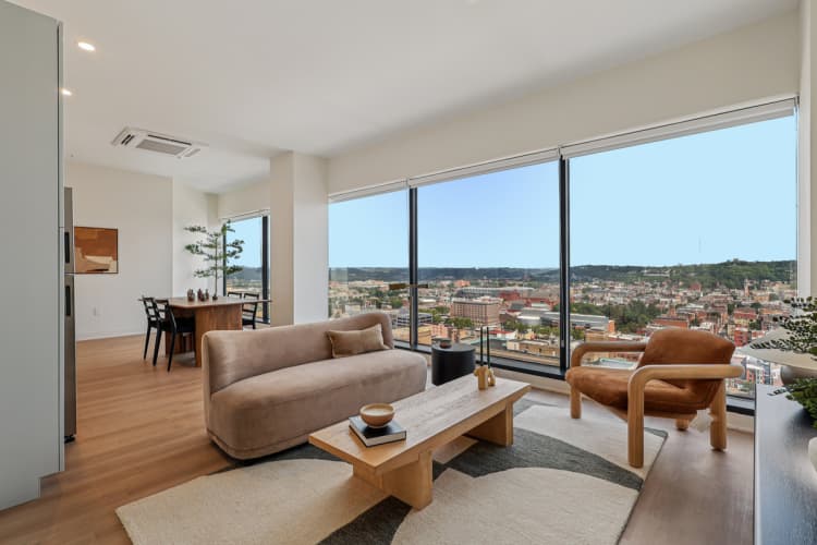 Cincinnati apartments for rent - image - A living room with a couch, chair, and table with a view of the city.