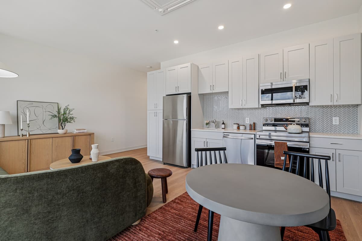Cincinnati apartments for rent - image - A modern kitchen with a green couch and a grey table.