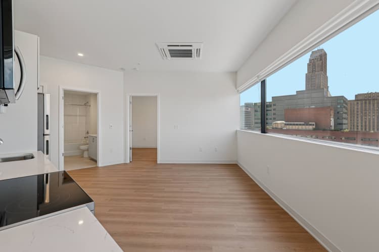 Cincinnati apartments for rent - image - A large empty room with wooden floors and a city view from the window.