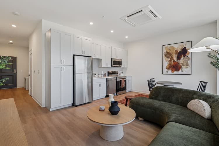 undefined apartments for rent - image - A modern kitchen with a green couch and a wooden table.