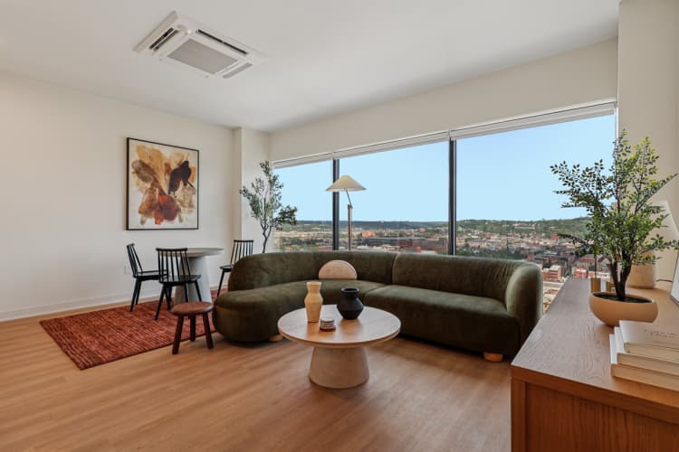 undefined apartments for rent - image - A living room with a green couch and a painting on the wall.