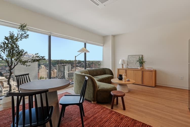 undefined apartments for rent - image - A living room with a view of the cityscape outside the window.