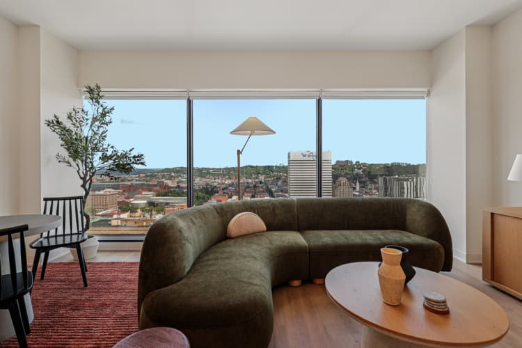 undefined apartments for rent - image - A living room with a green couch and a view of the city.