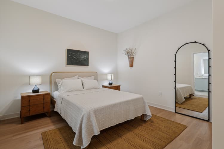undefined apartments for rent - image - A bedroom with a bed, nightstands, and a mirror.