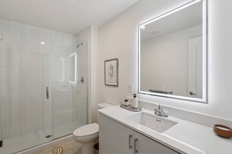undefined apartments for rent - image - A white bathroom with a toilet, sink, and mirror.